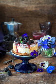 A mini blackberry cheesecake with blackberry sauce and edible flowers