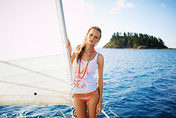 A young woman wearing a bikini and a top on a surfboard