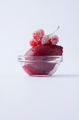 Red currant sorbet in a glass bowl against a white background