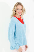 A blonde woman wearing a red top and a blue jumper