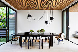 Dark dining table with classic chairs and pendant lights above the patio door