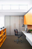 weiße Schreibtischplatte, schwarzer Drehstuhl und orangefarbenem Hängeschrank im Arbeitszimmer