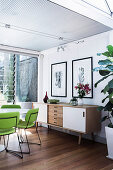 Lime green chairs around white table and sideboard in open dining area