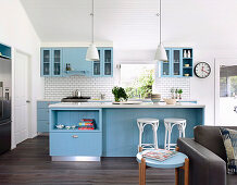 Open kitchen with blue cupboard fronts and white wall tiles