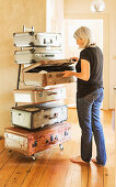 Blonde woman in front of handmade chest of drawers made from vintage suitcases and metal frame