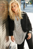 A young blonde woman wearing a tunic blouse and a black faux fur jacket