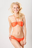 A young blonde woman wearing an orange bikini