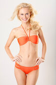 A young blonde woman wearing an orange bikini