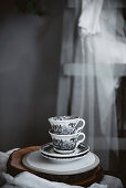 Two ceramic cups with drawing placed on plates on wooden table