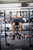 A young man performing a bar muscle-up on a pull-up bar