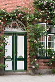 Historisches Backsteinhaus begrünt mit üppigem Rosenschmuck