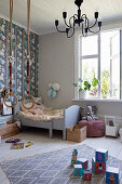 Wooden bed, gymnastic rings, soft toys and other toys in child's bedroom