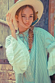 A young woman wearing a straw hat and a striped blouse with puffed sleeves