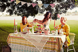 Three young women sitting at a festively laid garden table