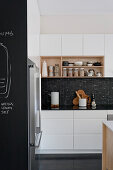 Modern black-and-white kitchen with shelves and chalkboard wall