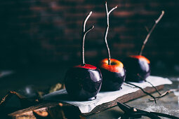 Halloween caramel apples with sticks on dark background