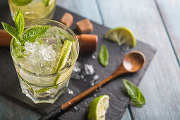 Mojito in glass on wooden blue table with lime and mint
