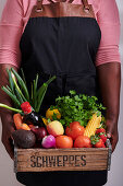 Afrikanische Frau hält Holzkiste mit Gemüse, Obst und Lebensmitteln