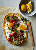 Chickpea flour flatbread topped with garlicky yoghurt, fried eggs, vine tomatoes and olives
