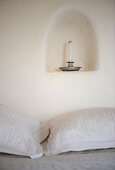 Kerzenhalter mit Kerze in einer kleinen Wandnische überm Bett