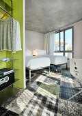 Twin beds in hotel room with concrete ceiling and patchwork carpet