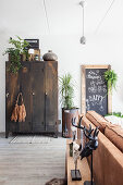 Vintage metal locker, houseplants, chalkboard and brown leather sofa in living room