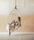Woman sits relaxed in a boho-style hammock with sheepskin