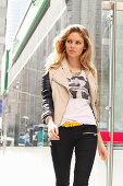 Junge blonde Frau in T-Shirt, Bikerjacke und schwarzer Hose