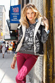 Junge blonde Frau in Shirt, Jacke und dunkelroter Hose