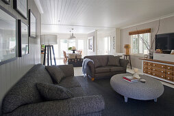Graue Sofas und runder Korbtisch im Wohnzimmer im Hamptons-Stil