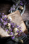 Quail eggs and purple flowering branches between open pages of an old book