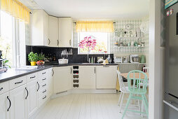 Küchenzeile übereck und Essbereich in heller Wohnküche mit weißem Dielenboden
