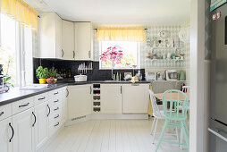 L-shaped kitchen counter in bright kitchen-dining room with white wooden floor