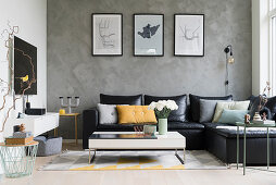 Black leather couch and coffee table in open-plan interior with grey wall