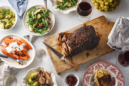 Big festive dinner with slow-roasted pork and various side dishes with vegetables