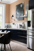 Blick auf schwarze Küchenzeile, Kühlschrankkombination mit Edelstahl-Türen und Essbereich