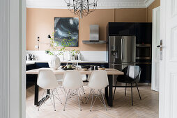 White classic chairs in dining area in front of stainless steel fridge-freezer in kitchen-dining room