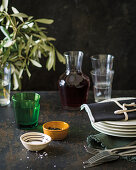 An Italian table laid with crockery, cutlery, pepper, salt, red wine and a spring of olives