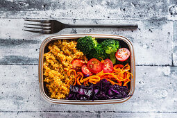 A bento box with quinoa, red cabbage, carrots, tomatoes and broccoli