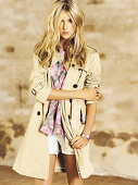 Blonde Frau in pastellfarbener Bluse, Shorts und Trenchcoat