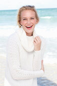 Junge blonde Frau in weißem Pullover am Meer