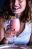 A young woman drinking a strawberry shake with a straw