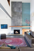 Grey leather sofa set and fireplace with floor-to ceiling concrete chimney breast in lounge