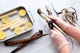 Black salsify being peeled and placed in lemon water