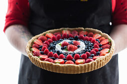 A woman holding a vegan berry pudding tart