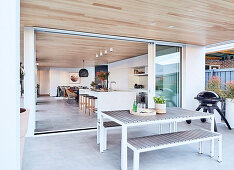 Moderner Essplatz auf überdachter Terrasse, Blick in offenen Wohnraum