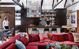 Red upholstery set with pillows, kitchen island, Moroccan encaustic tiles and antique, Moroccan door as a room divider, woman and man in the background