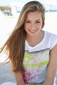 Junge blonde Frau mit buntem Shirt am Strand