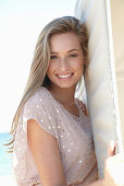 A young blonde woman on a beach wearing a beige polka-dot dress