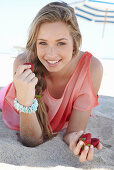 A young blonde woman on a beach wearing a salmon-coloured, off-the-shoulder top